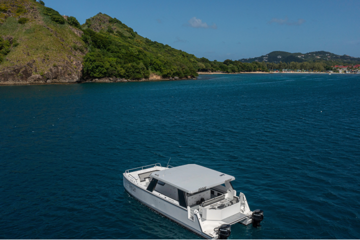 White boat on blue water near green hills under a clear sky.