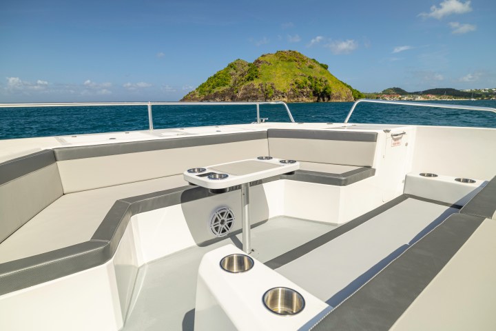 Boat seating area with island view across the ocean under a clear blue sky.