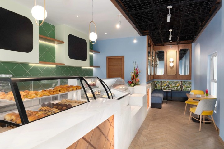 Modern bakery interior with display cases, pastries, and seating area.